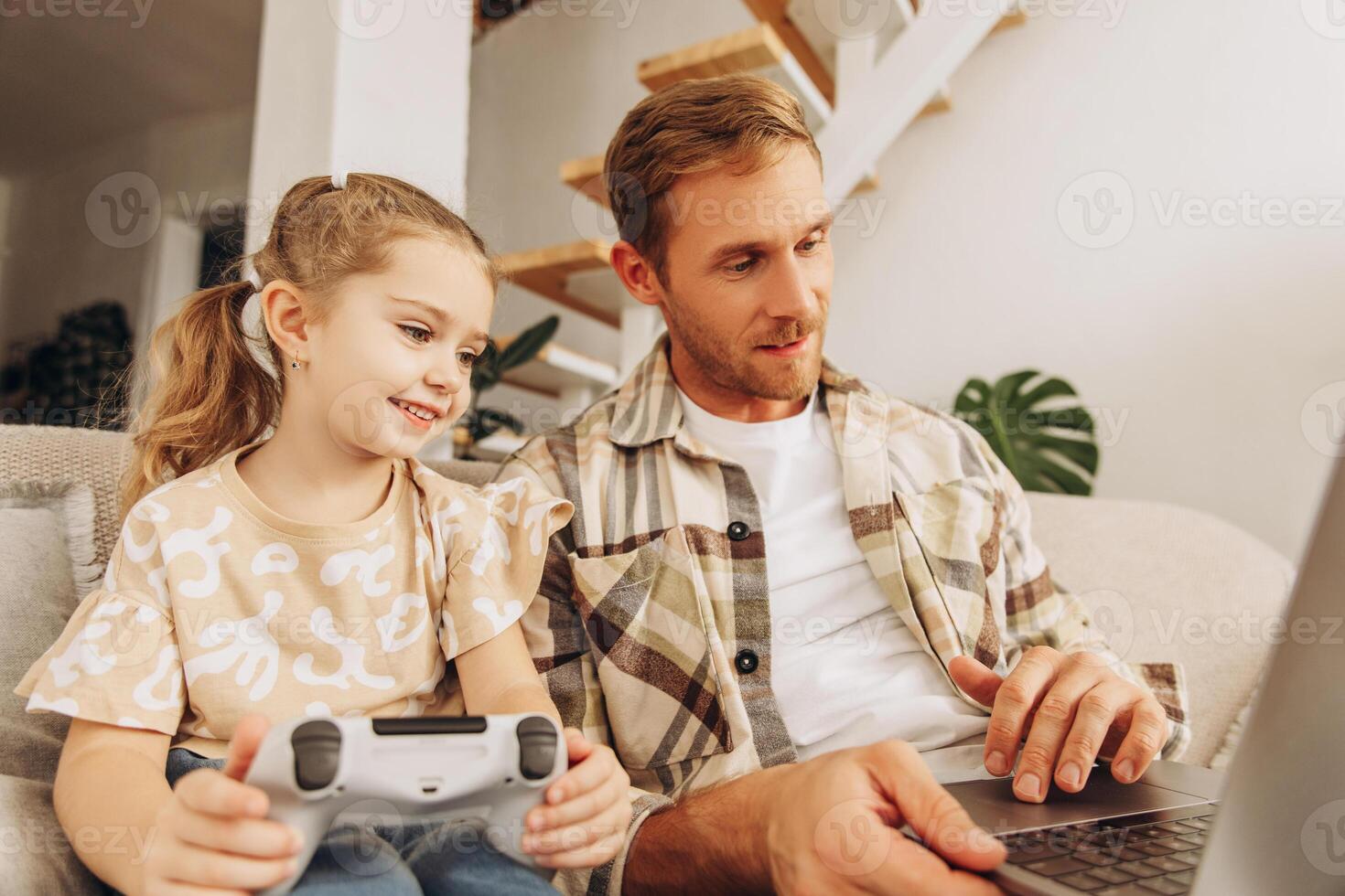 Handsome father and little daughter together sitting on comfortable sofa, holding joystick photo