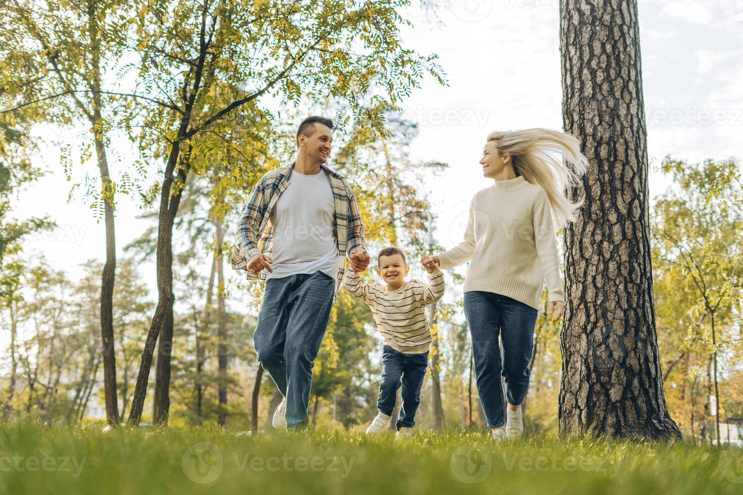 Happy family, beautiful mother, smiling father and little son together walking in the park photo