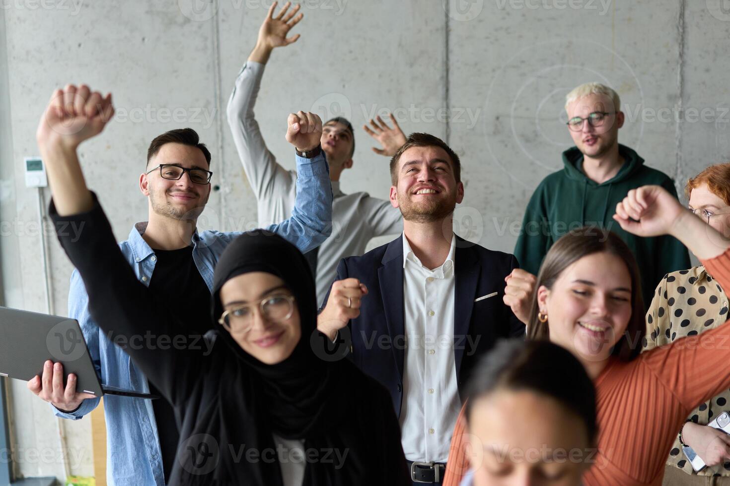 A diverse team of business professionals ecstatically celebrating their success in a modern office, expressing triumph and unity after achieving their goals photo