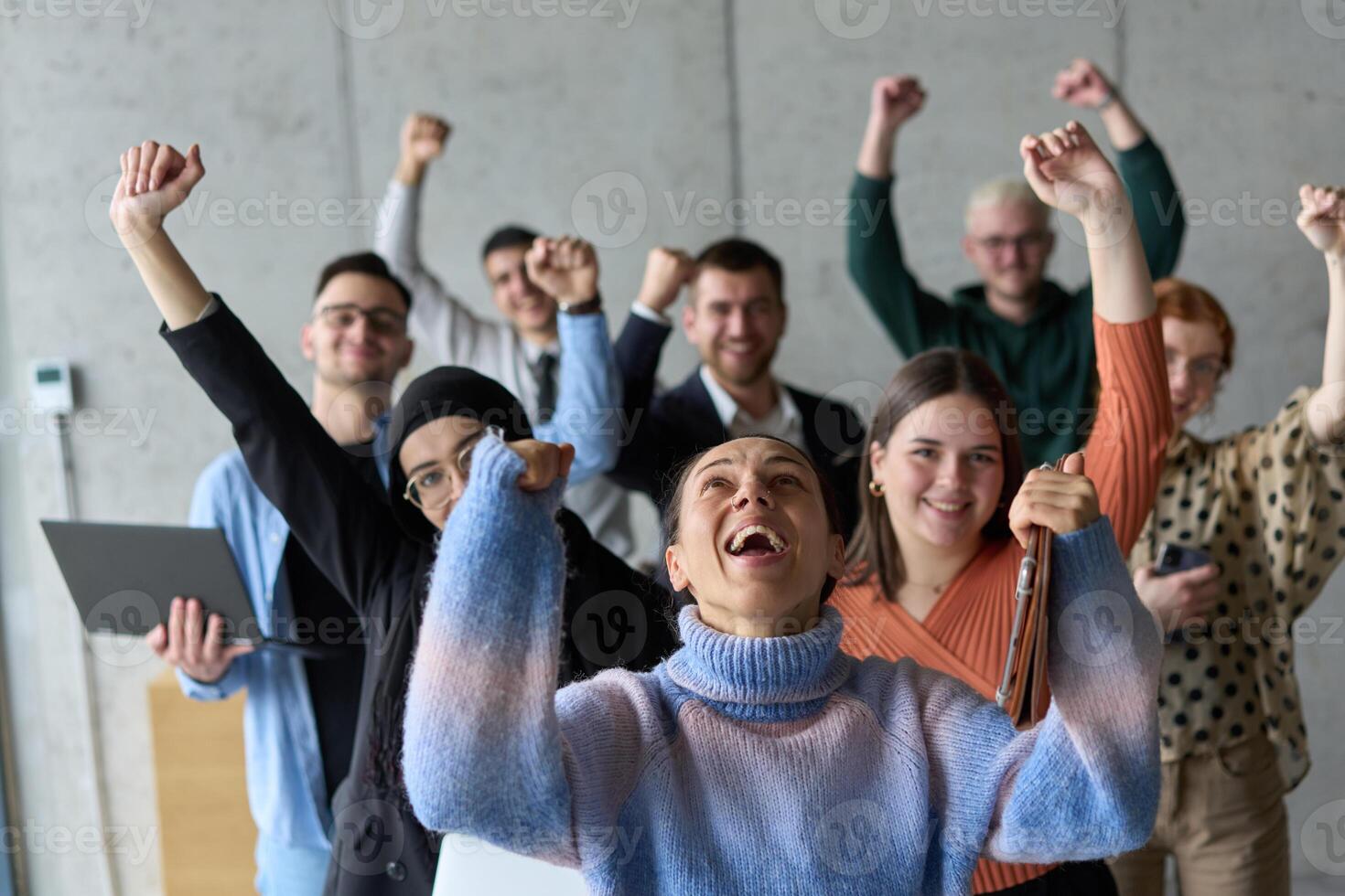 A diverse team of business professionals ecstatically celebrating their success in a modern office, expressing triumph and unity after achieving their goals photo
