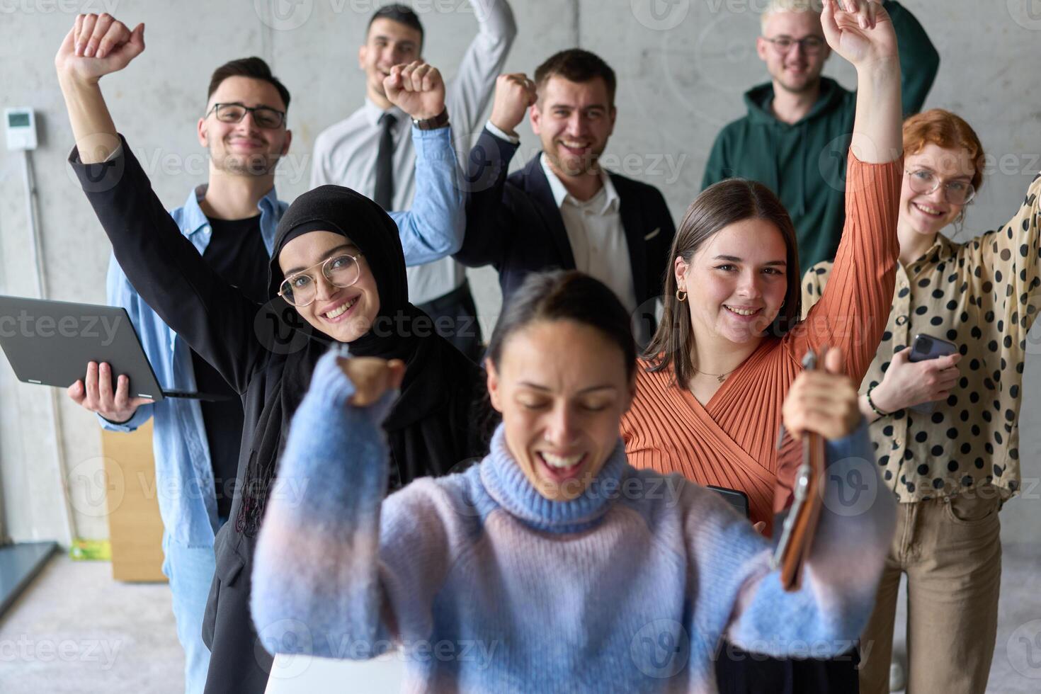 A diverse team of business professionals ecstatically celebrating their success in a modern office, expressing triumph and unity after achieving their goals photo