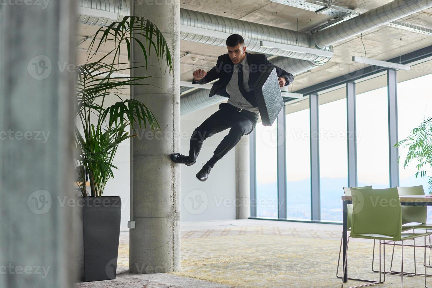 A businessman ecstatically jumping in a modern office, holding a briefcase in his hands, celebrating a moment of success and triumph. photo