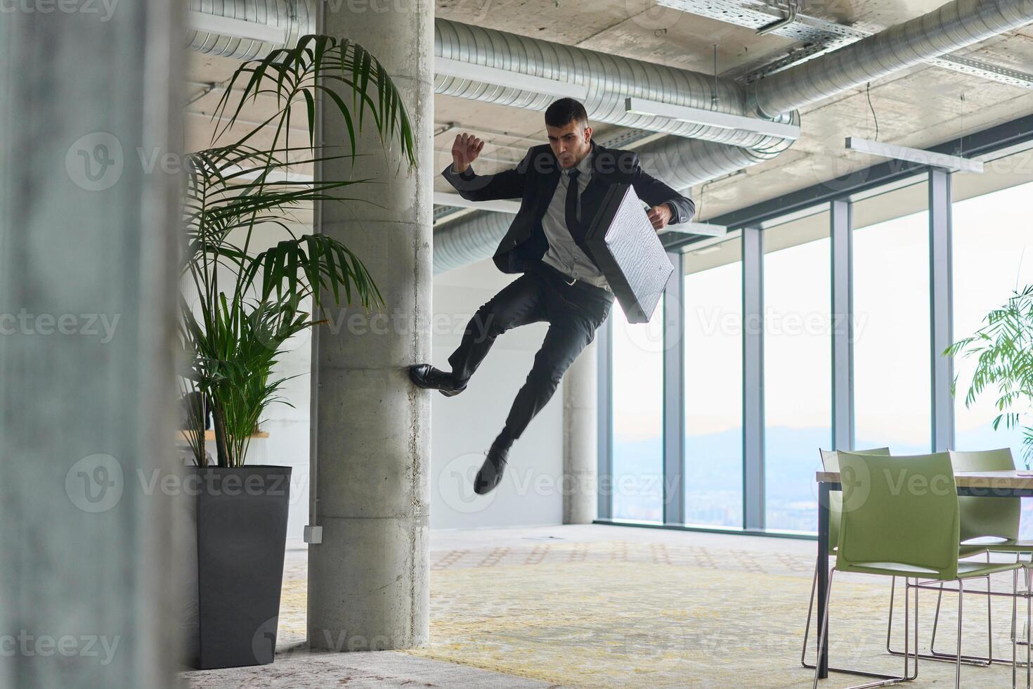 A businessman ecstatically jumping in a modern office, holding a briefcase in his hands, celebrating a moment of success and triumph. photo