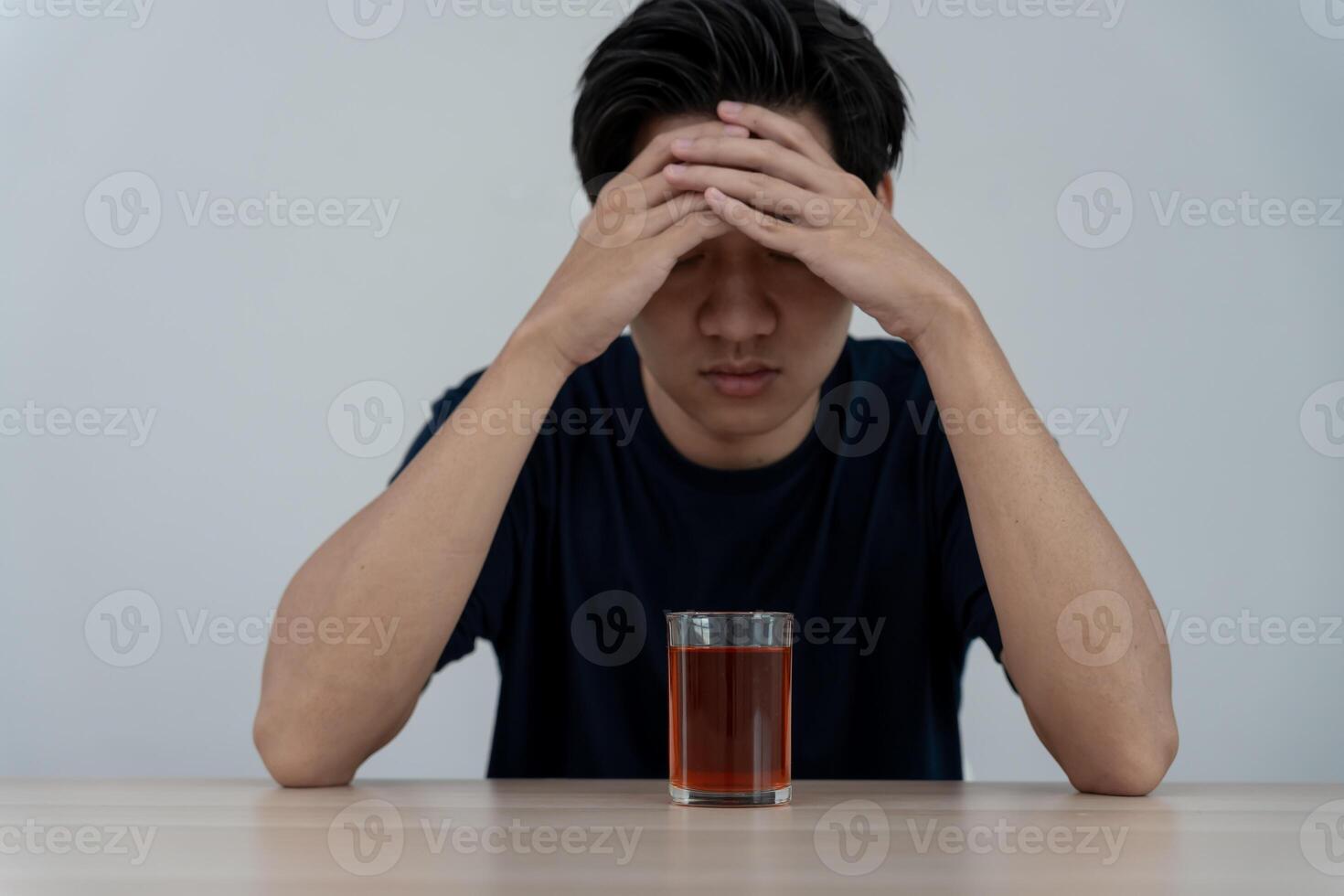 Depressed young Asian man addicted feeling bad drinking whiskey alone at home, stressed frustrated lonely drinking alcohol suffers from problematic liquor, alcoholism, life and family problems photo