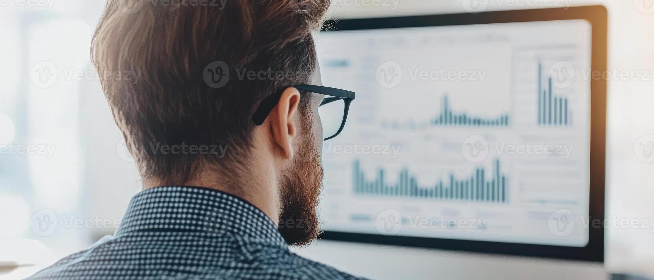 Focused man analyzing data trends on a computer screen in a modern office environment. photo
