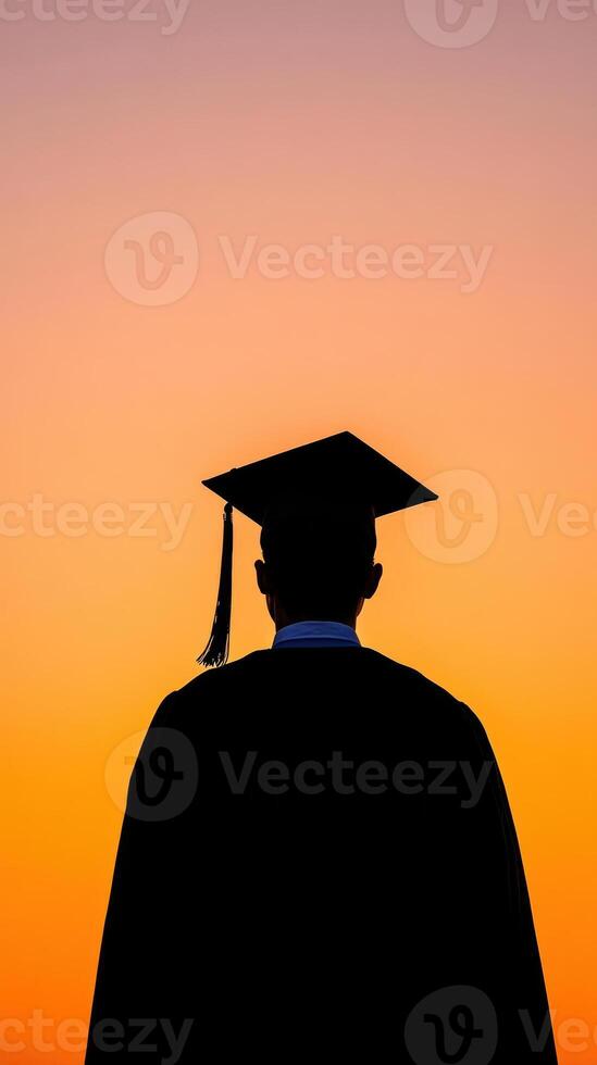 Silhouette of a graduate wearing a cap against a vibrant sunset sky. photo
