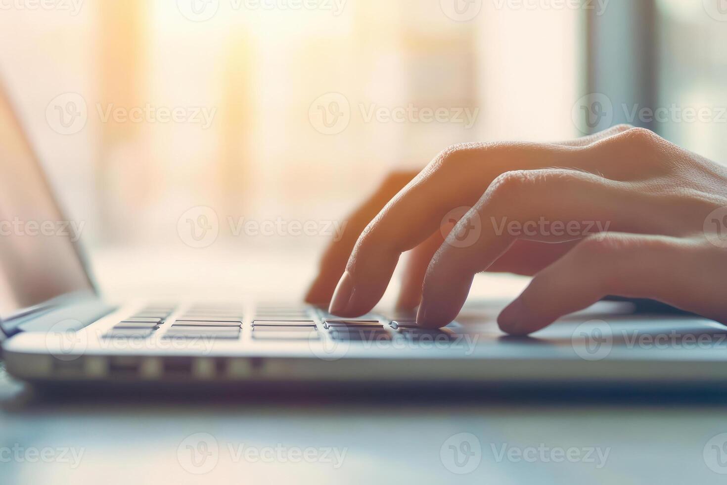 Close-up of hands typing on a laptop in a bright, modern workspace. photo