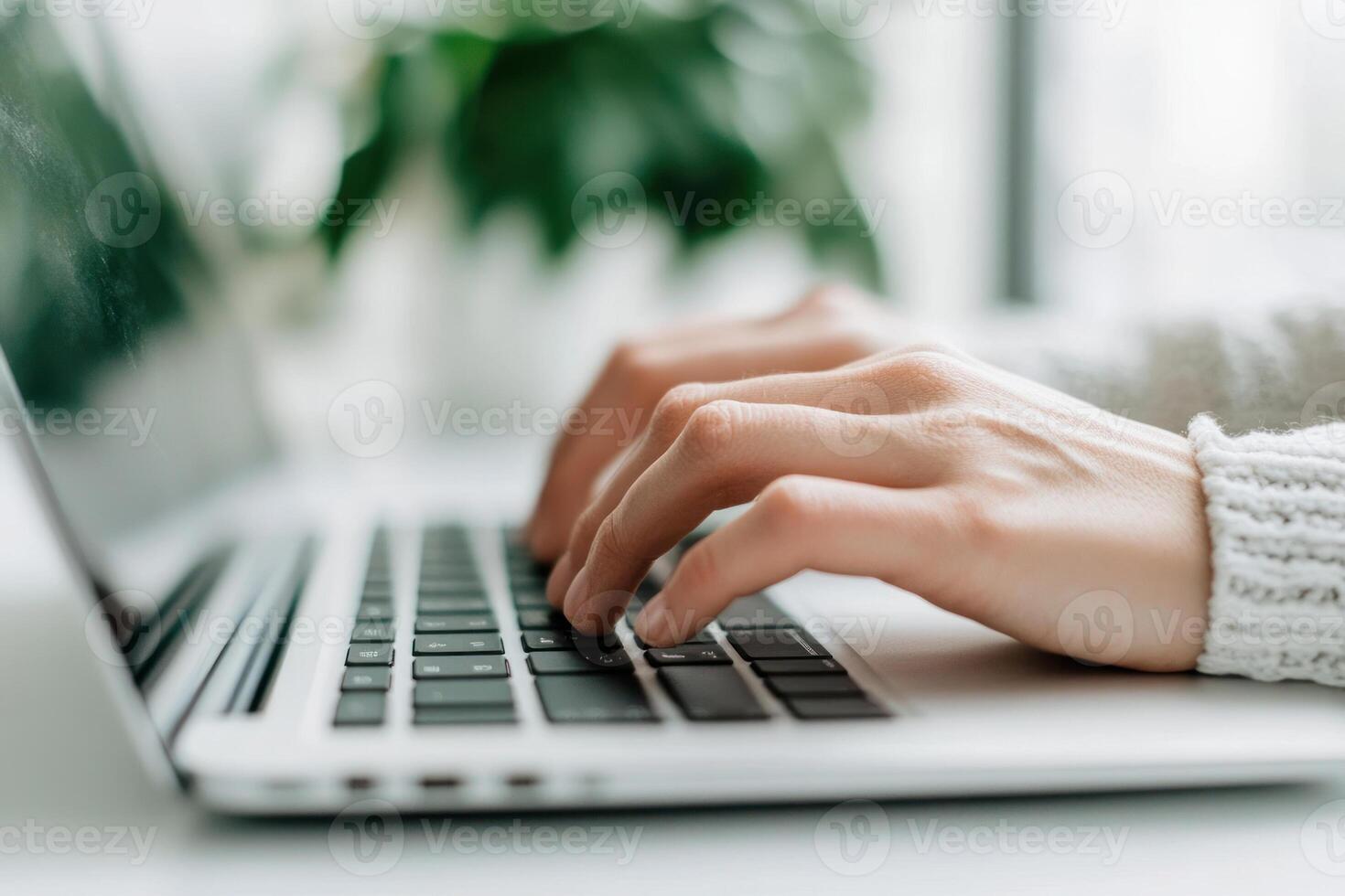 Close-up of hands typing on a laptop keyboard in a modern office setting. photo