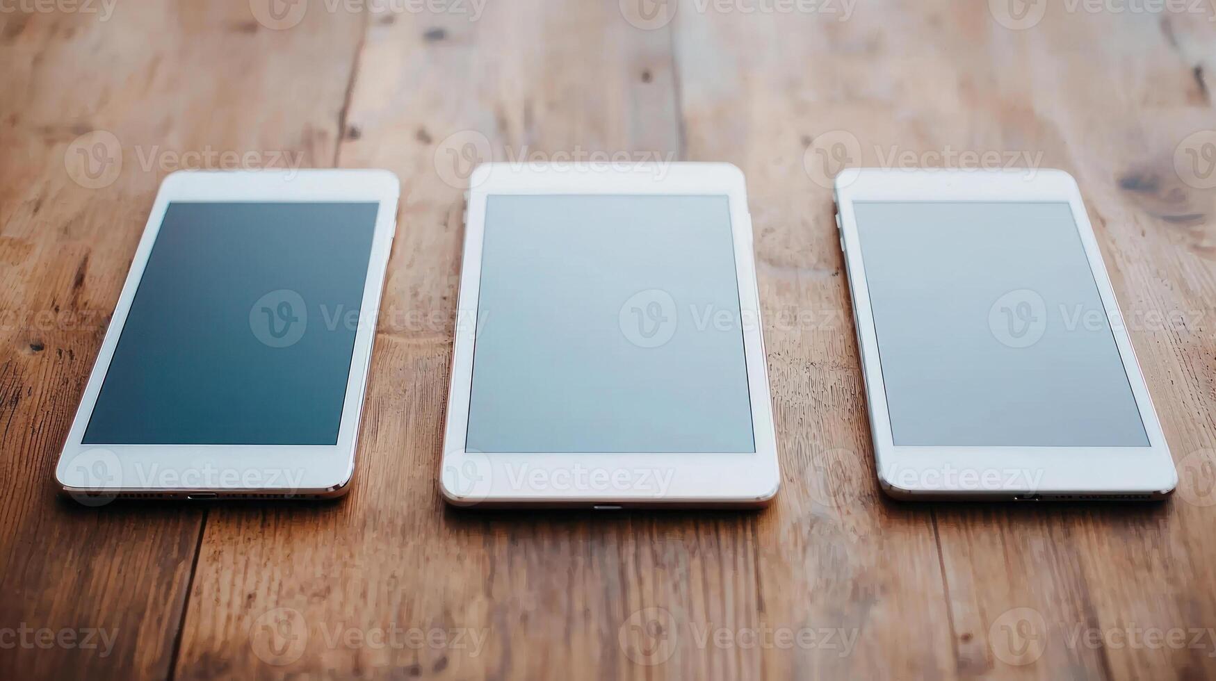 Three sleek tablets arranged on a wooden surface, showcasing modern design and versatility. photo