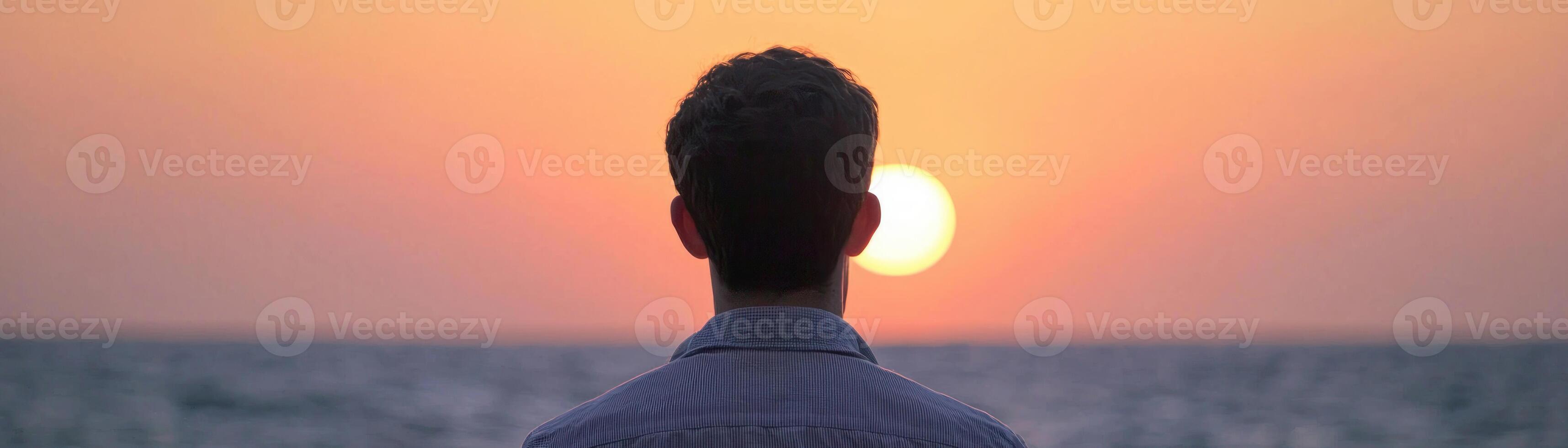 A person contemplating life while watching a sunset by the ocean. photo