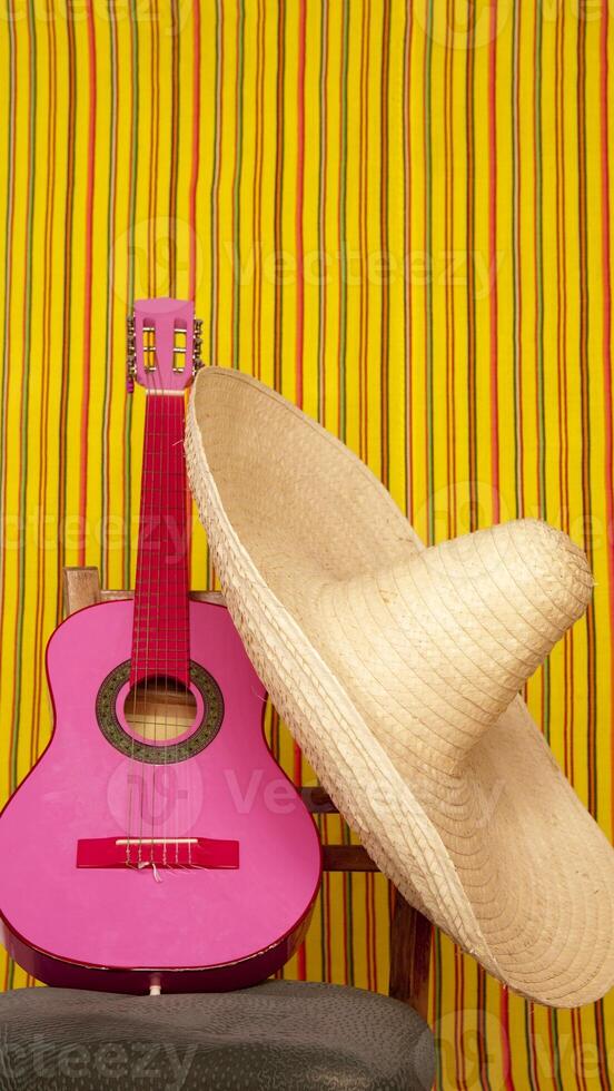 A pink guitar and a sombrero sit on a chair photo