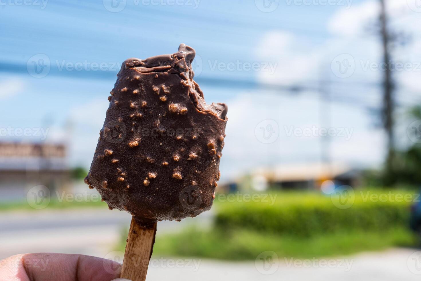 Bitten chocolate popsicle ice cream bar with crushed peanut nuts photo