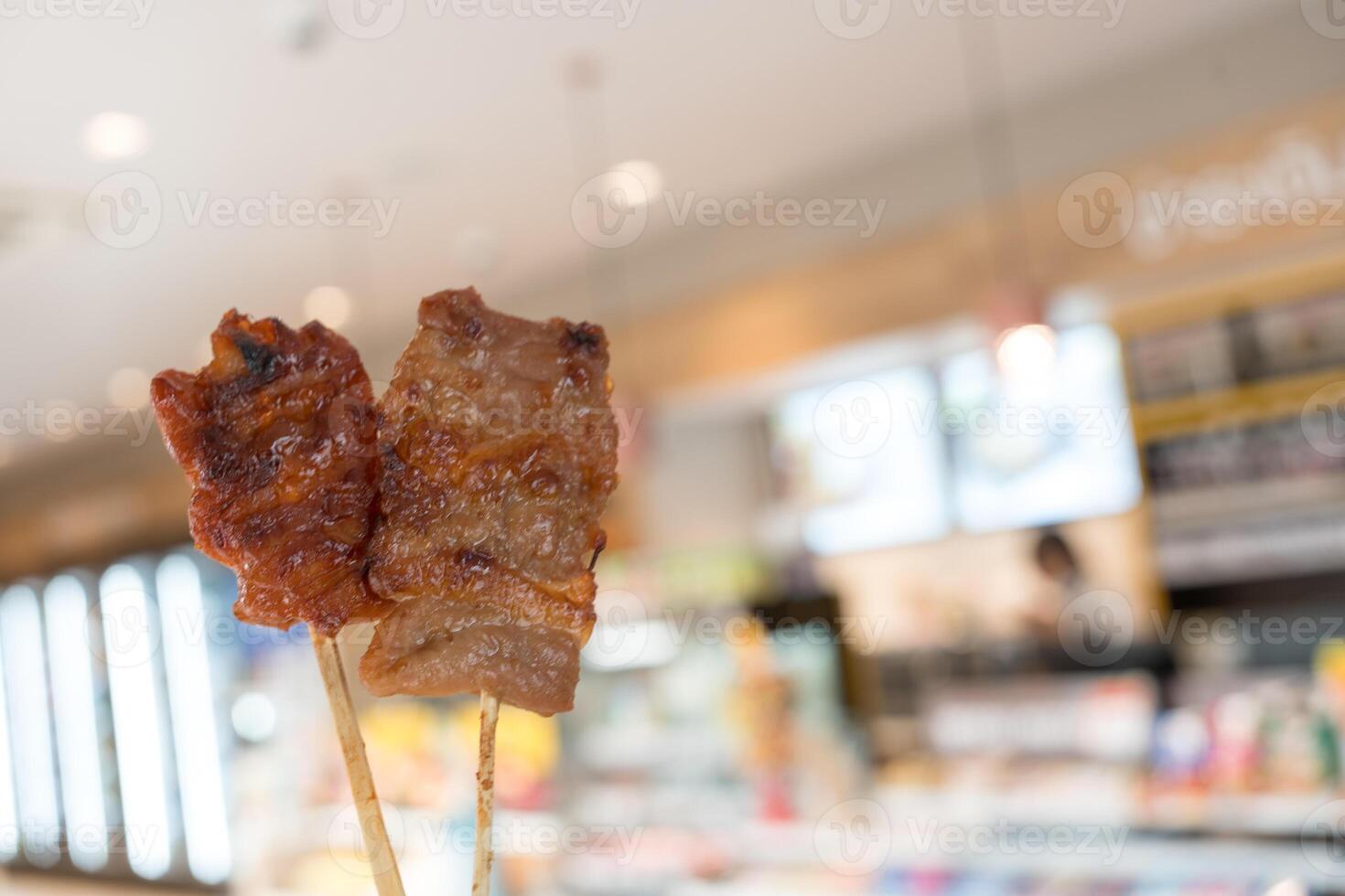 Holding a Thai grilled pork and chicken skewer. photo