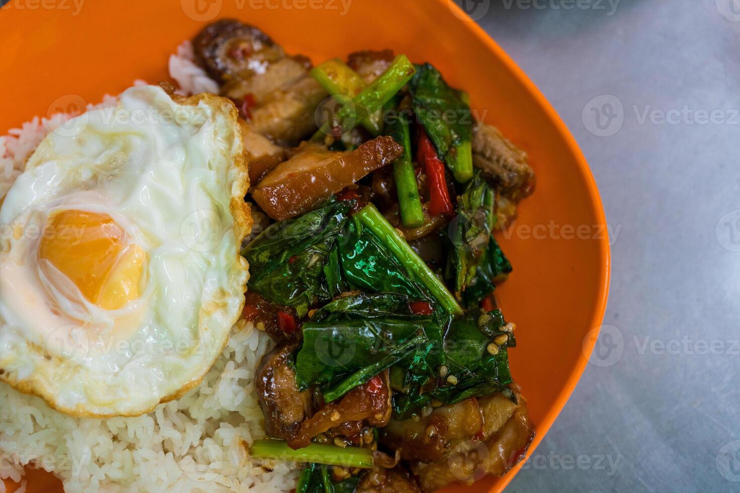 Stir fried kale with crispy pork served with rice and egg photo