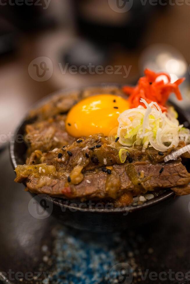 Roast Wagyu beef rice and raw egg bowl in a black bowl. photo