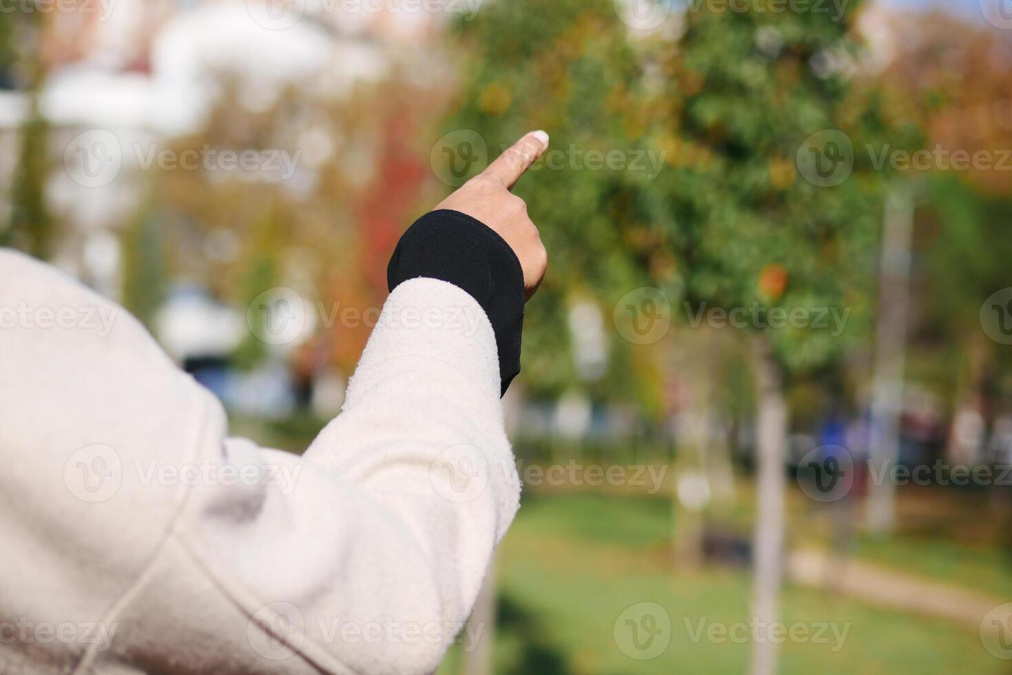 A person is enthusiastically pointing towards the trees in a lovely park photo