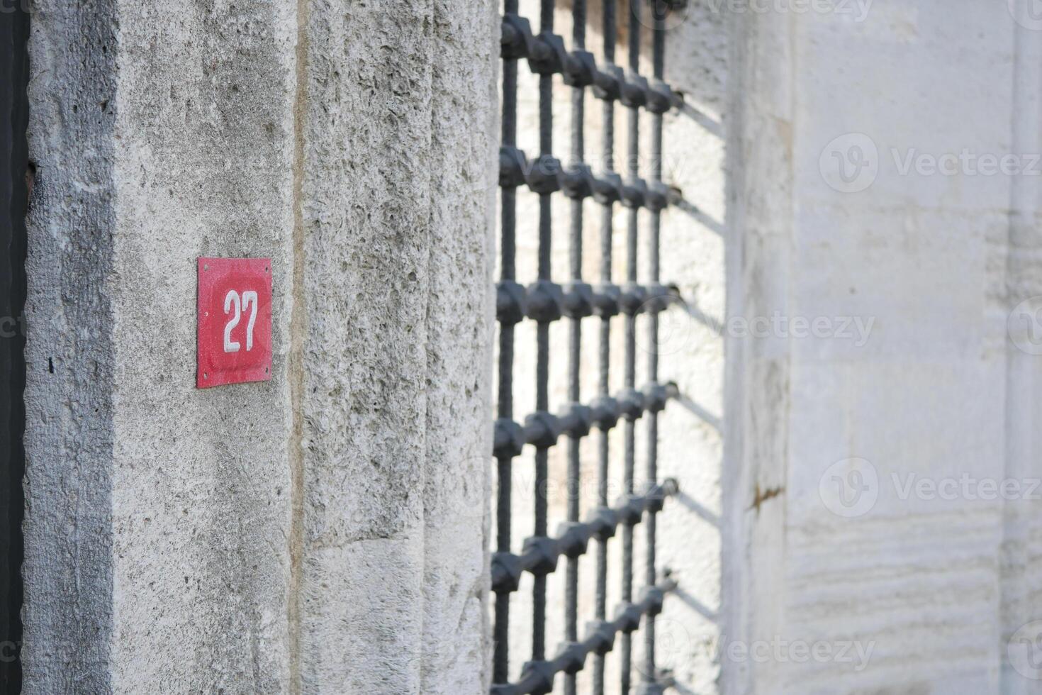 A Numbered Jail Cell Door Featuring Sturdy Metal Bars and a Concrete Wall photo