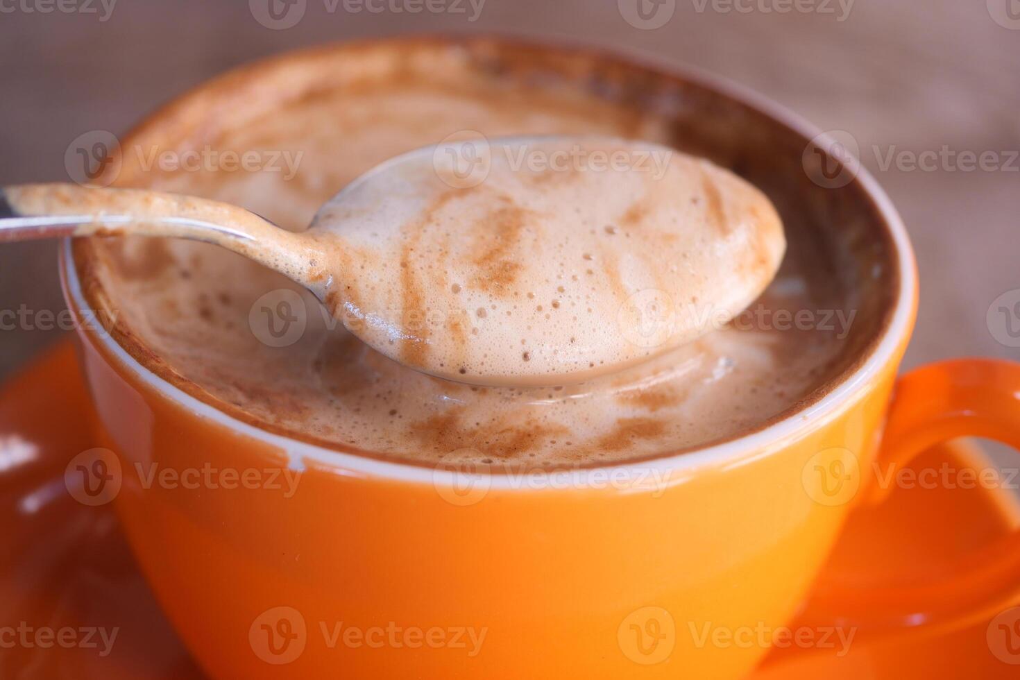 Enjoying a delicious cup of coffee served in a stylish orange cup along with a spoon photo