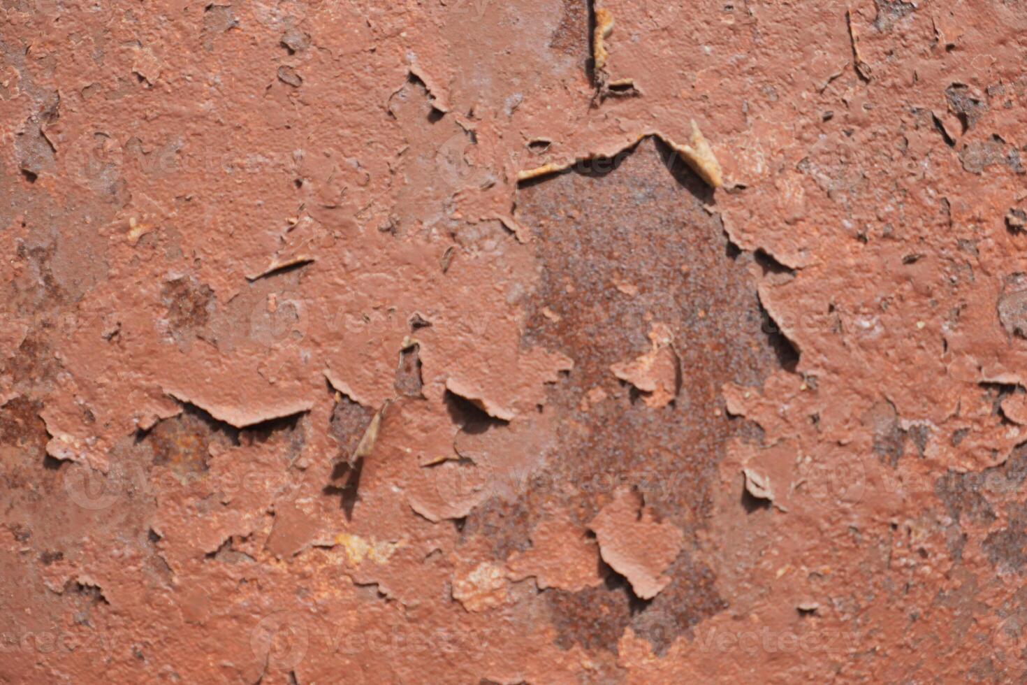 An ancient and weathered red surface exhibiting flaking paint and a rich texture throughout photo