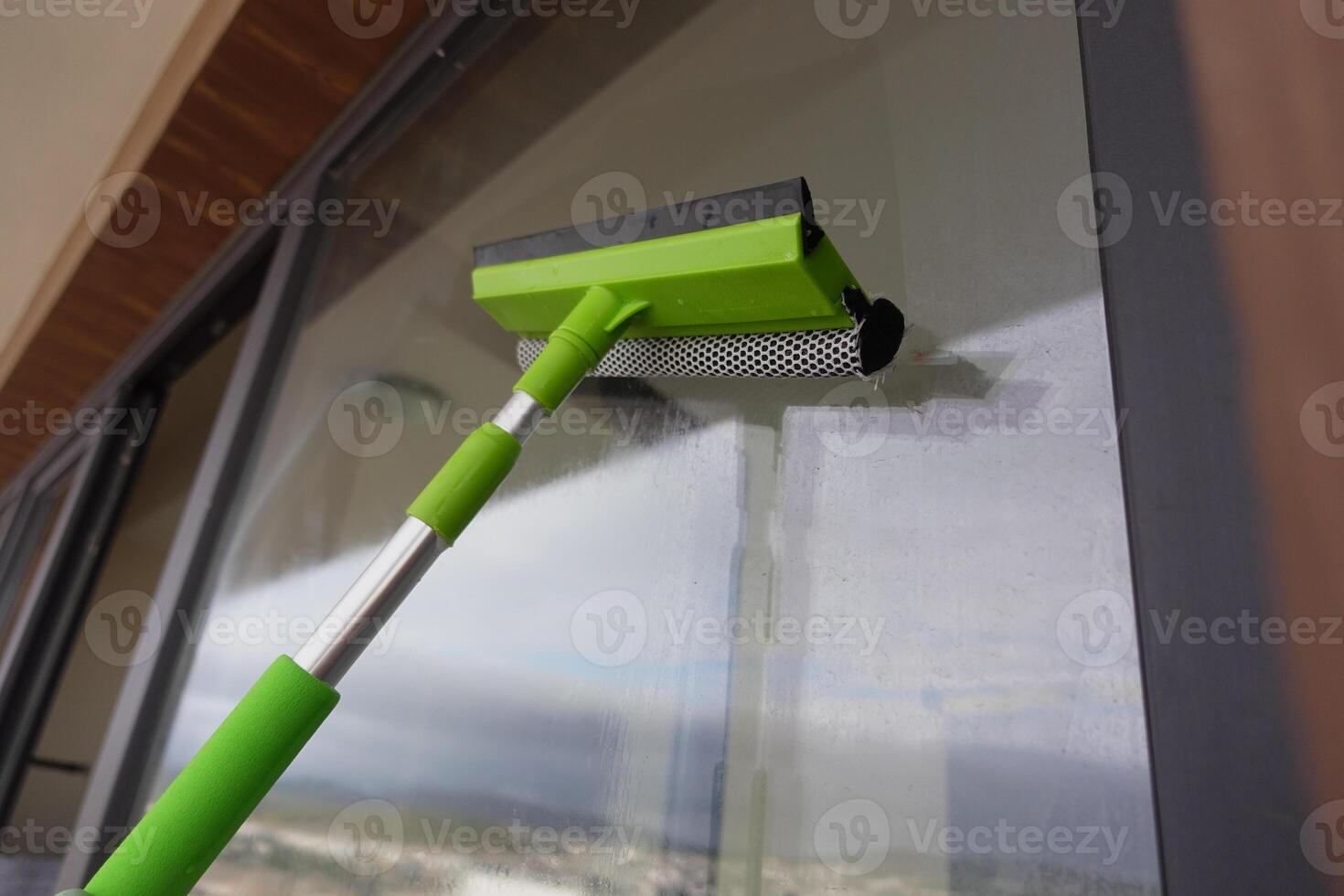Rubber squeegee cleans a soaped window. photo