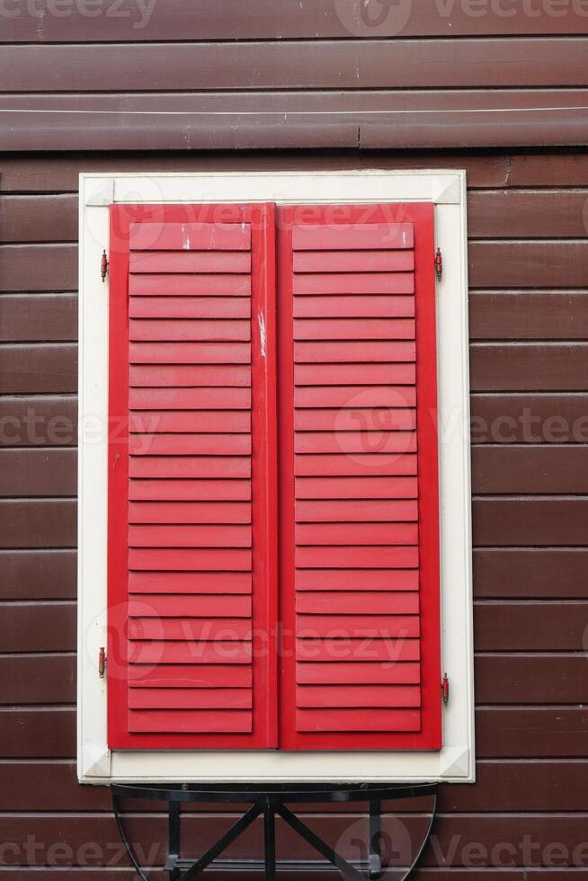 The vibrant and striking red shutters meticulously placed on a rustic wooden wall photo