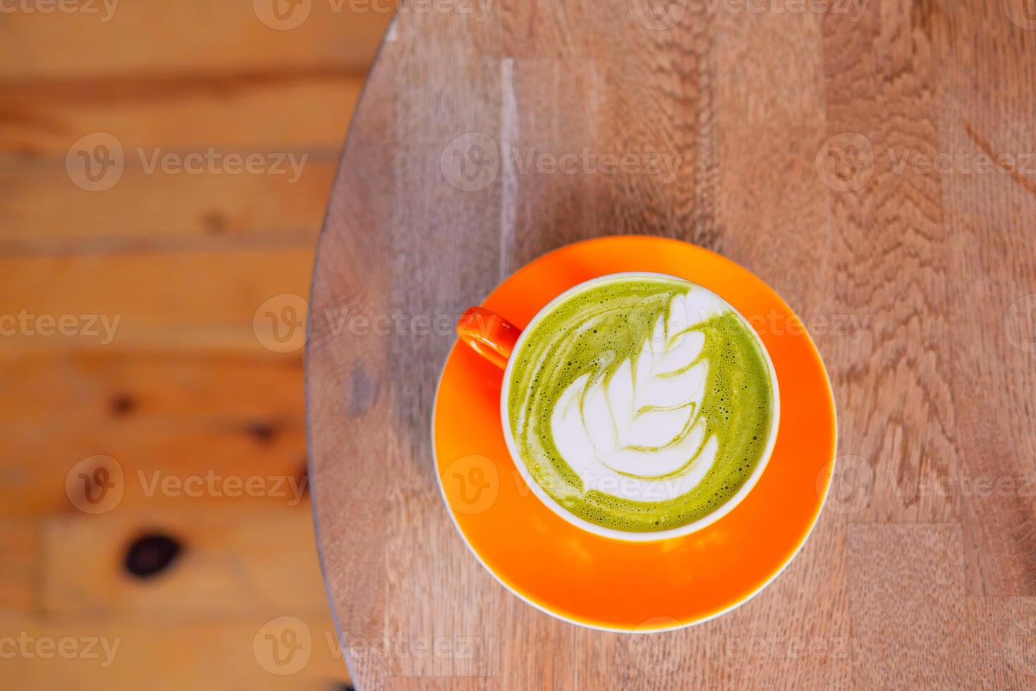 A delicious Matcha Latte beautifully presented with Leaf Art on a rustic Wooden Table photo