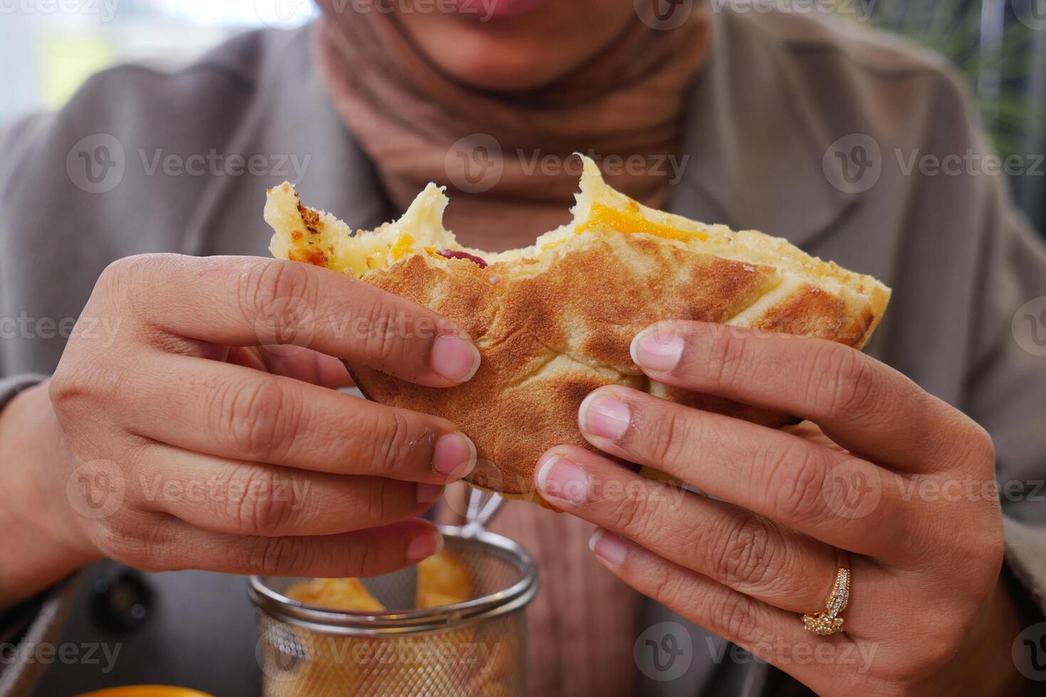 A CloseUp of Hands Enjoying a Delicious Savory Flatbread Topped with Melted Cheese photo