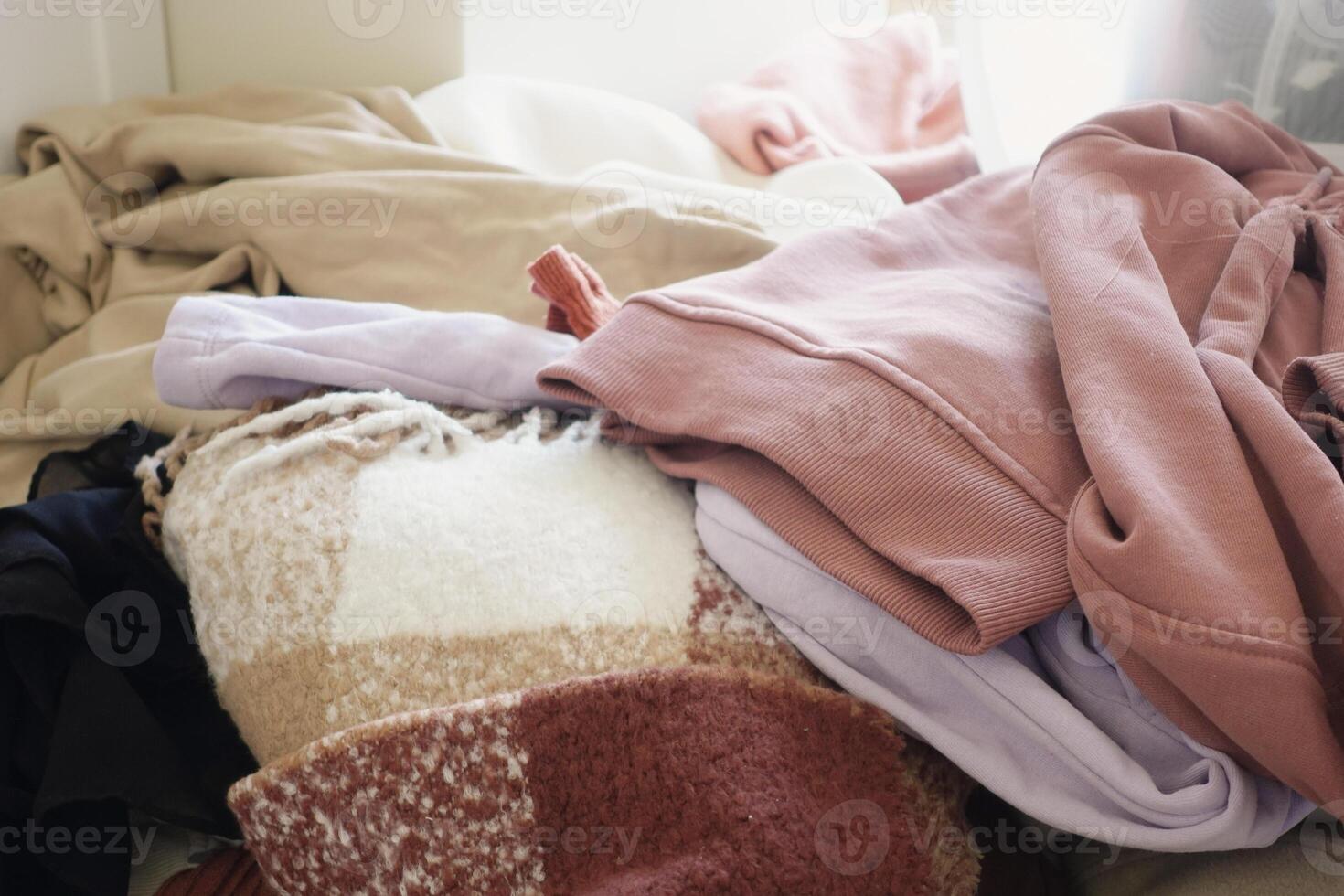 A Cozy Pile of Warm Clothing is Neatly Arranged on a Comfortable Bed for Relaxation photo