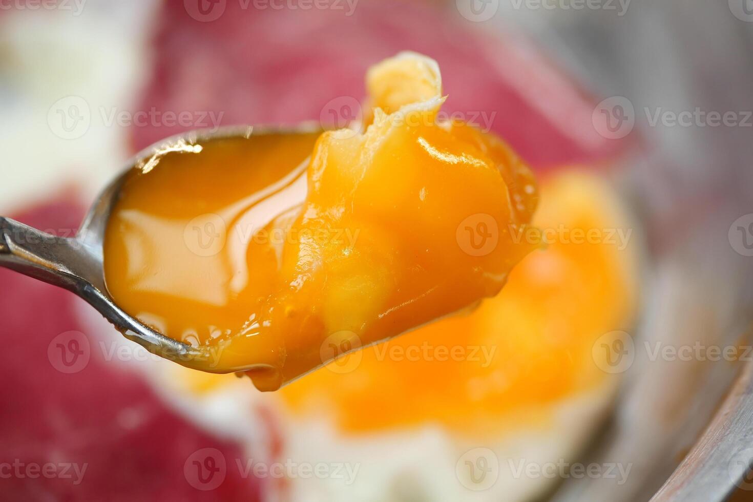 CloseUp of a Spoon with a Runny Egg Yolk on Fried Egg Whites, a tasty and healthy breakfast photo