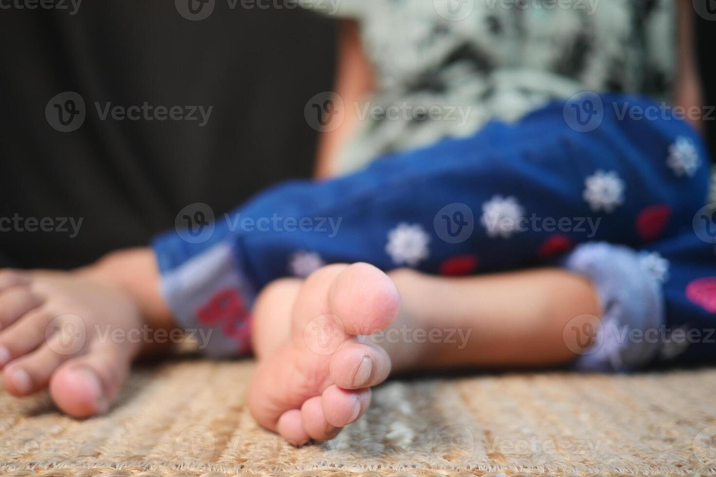 The Playful and Carefree Child is Sitting on a Soft Rug, Showcasing Their Joyful Feet photo