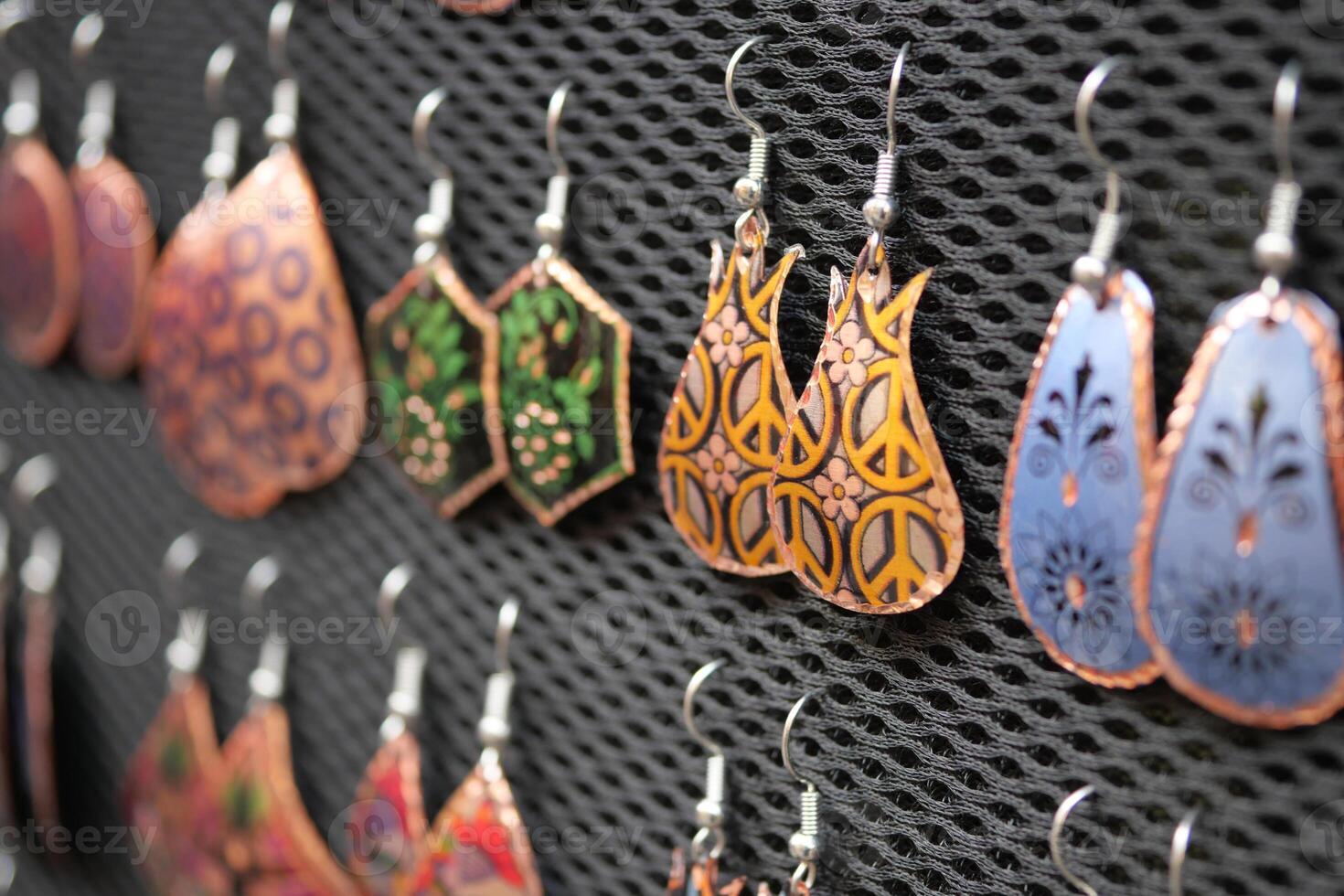A Variety of Colorful Handmade Earrings Beautifully Displayed on a Mesh Background photo