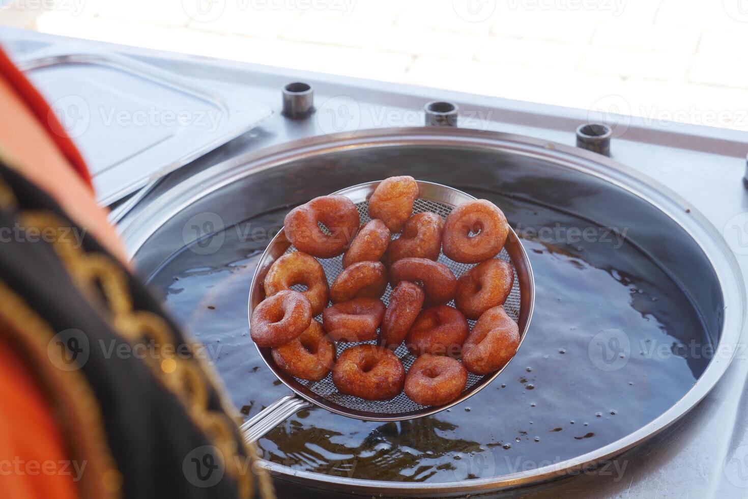 Freshly fried donuts are being prepared in hot oil, creating a delightful aroma in the air photo