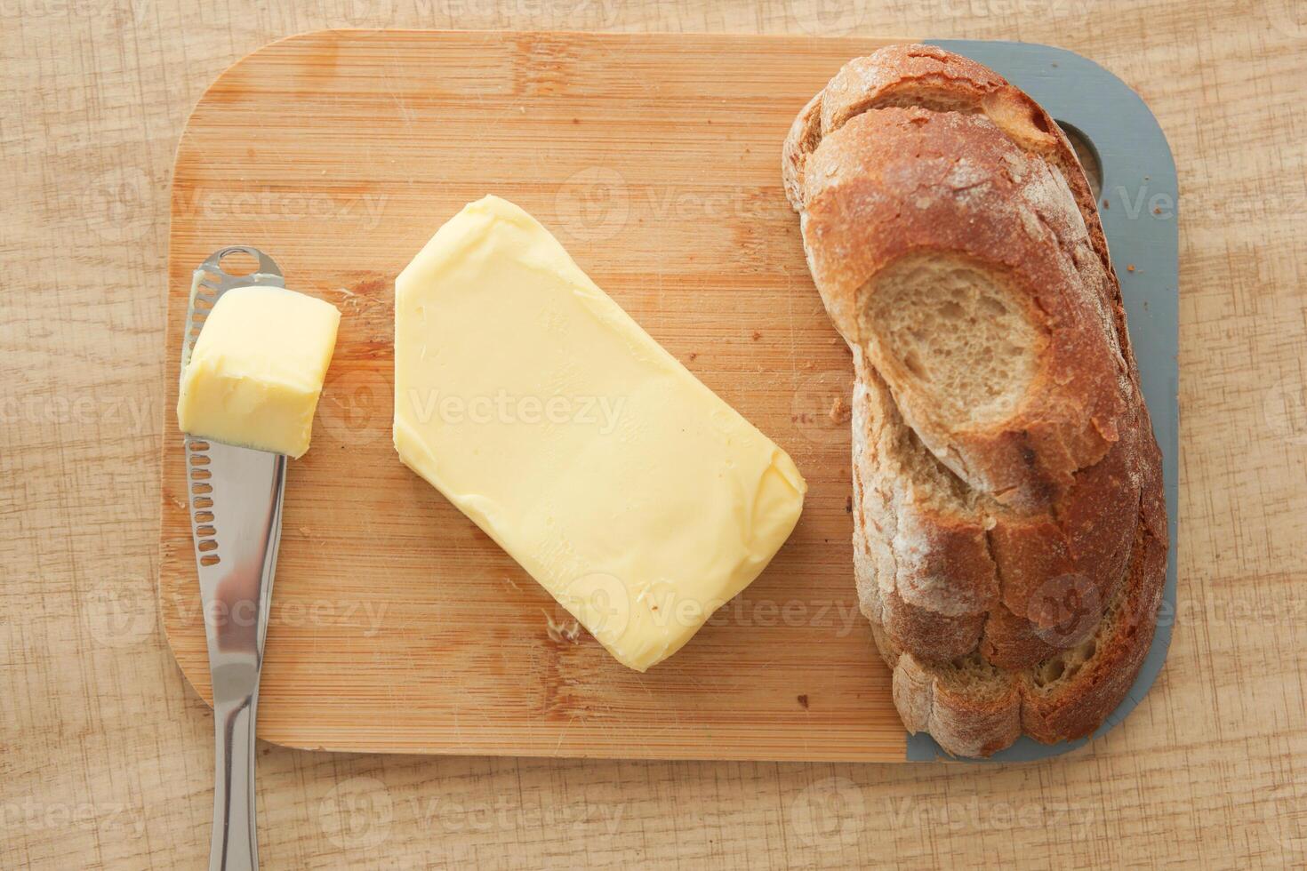 A Delicious Freshly Baked Bread with Creamy Butter on a Rustic Wooden Cutting Board photo