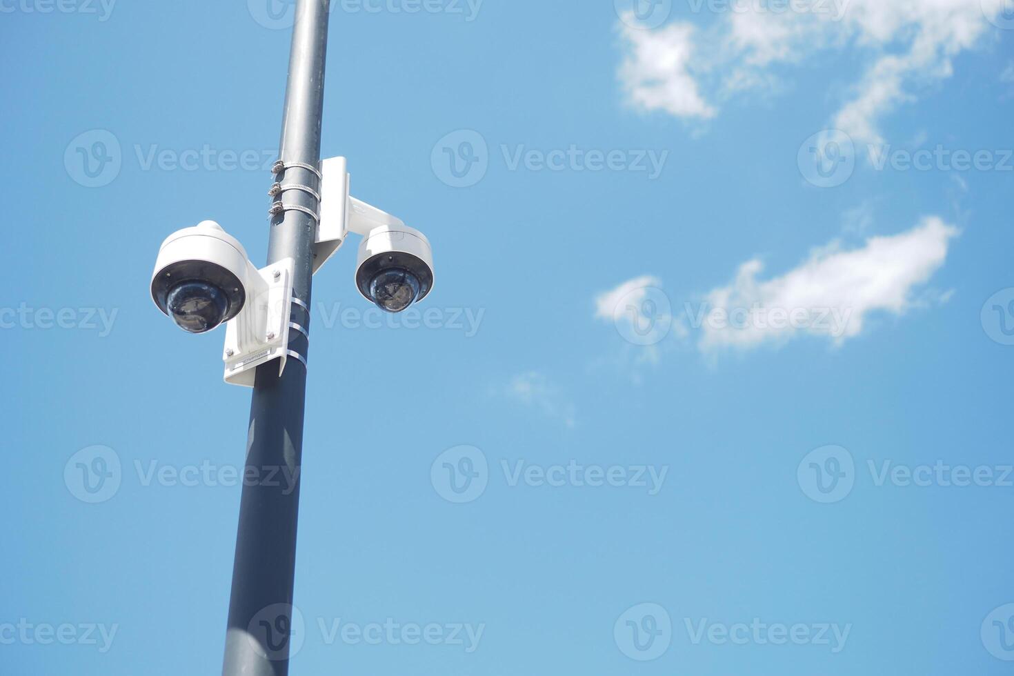 A modern surveillance camera is positioned on a clear day, capturing the surrounding environment photo
