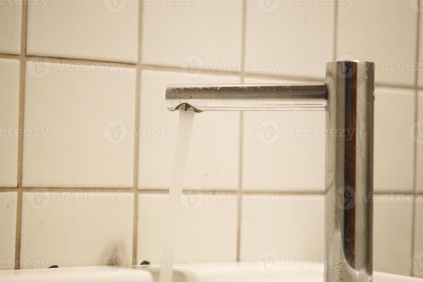 A contemporary faucet with water cascading effortlessly in a pristine, welcoming bathroom space photo