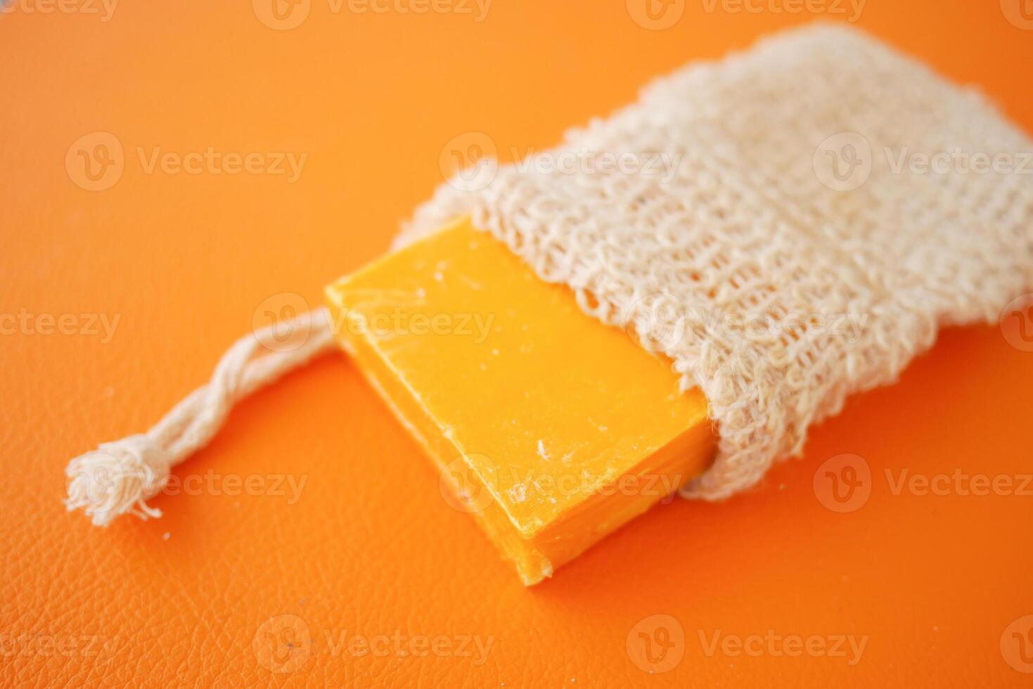 Handmade Soap in Jute Pouch on Vibrant Orange Background photo
