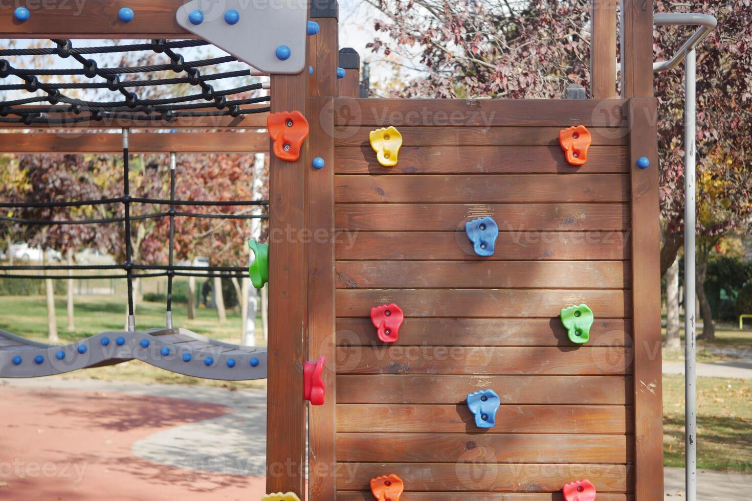 A bright and colorful climbing wall can be found at a playground, perfect for kids to enjoy photo