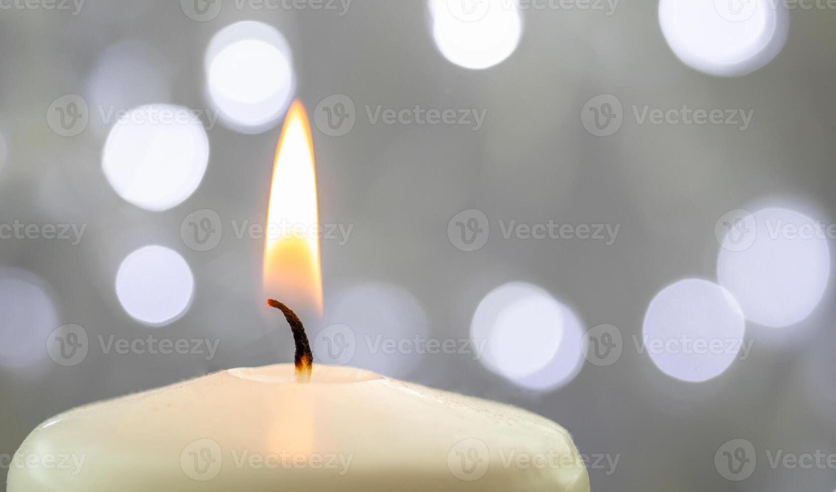 Close up of one burning candle with blurred Christmas light background photo