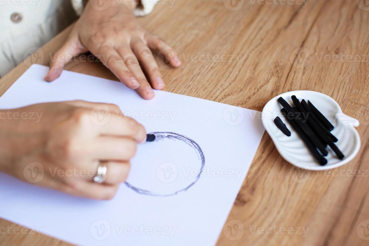 Hand Drawing Circle with Marker on Paper at Wooden Table photo