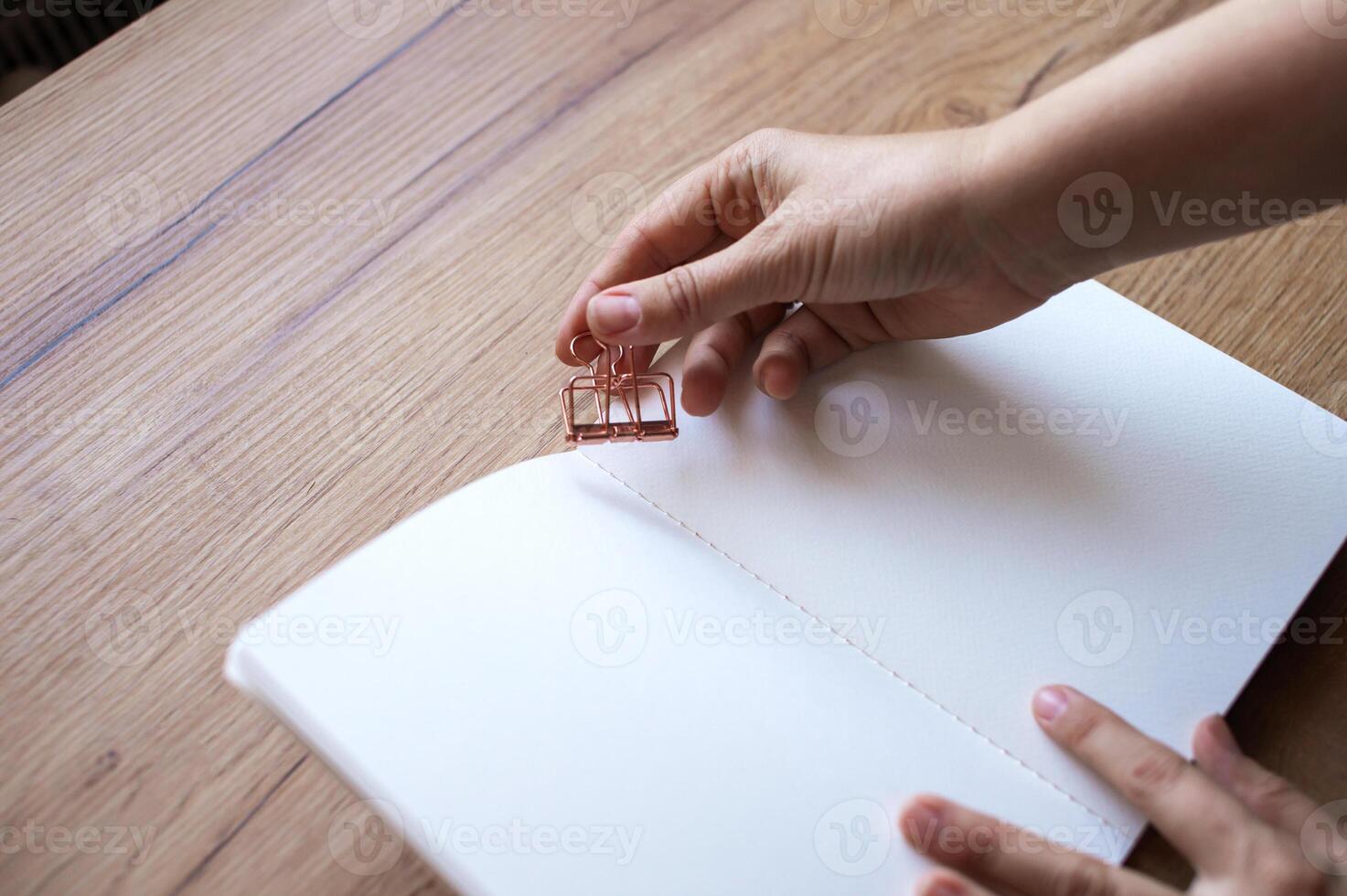 Hand Clipping a Binder to Paperwork on a Desk photo