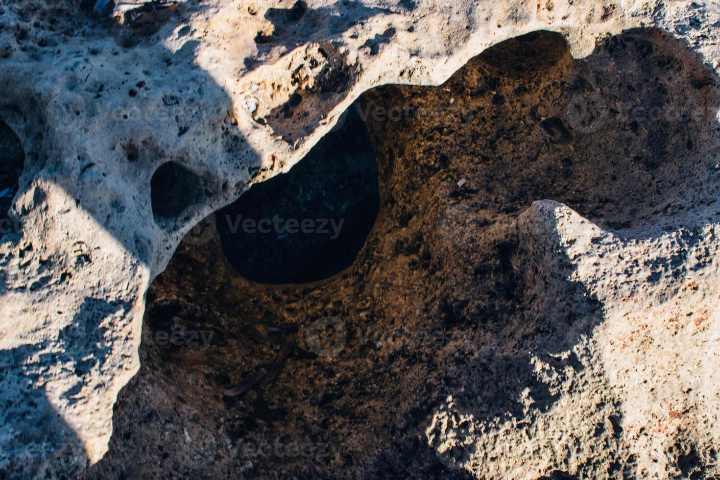 a textured landscape of wet, rocky terrain with shallow pools of water, surface appears rugged and uneven, showcasing natural erosion patterns photo