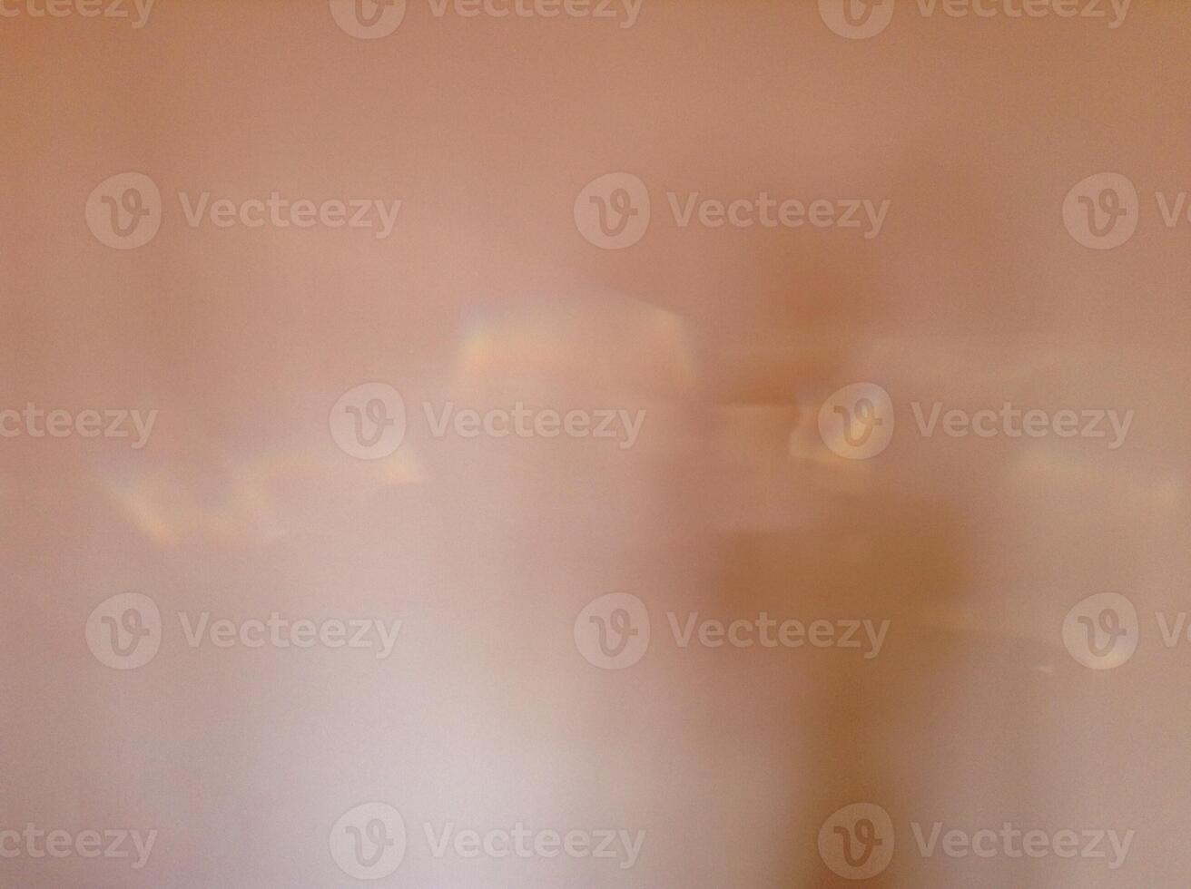 Blurry abstract peach colored background with patches of reflected light. photo