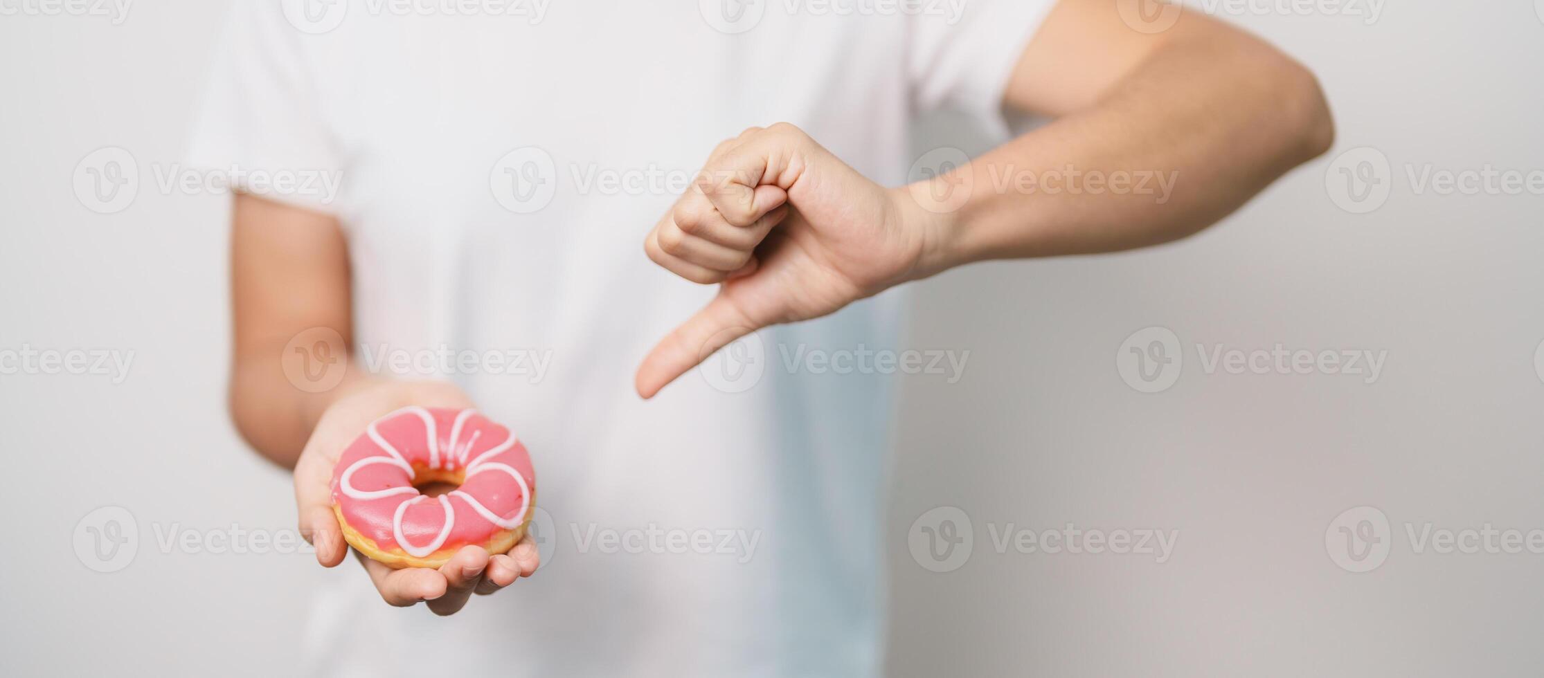 woman hand hold pink Donut, choose stop eating sweet is Unhealthy ealthy food. Dieting control, Weight loss, Obesity, eating lifestyle and nutrition concepts photo