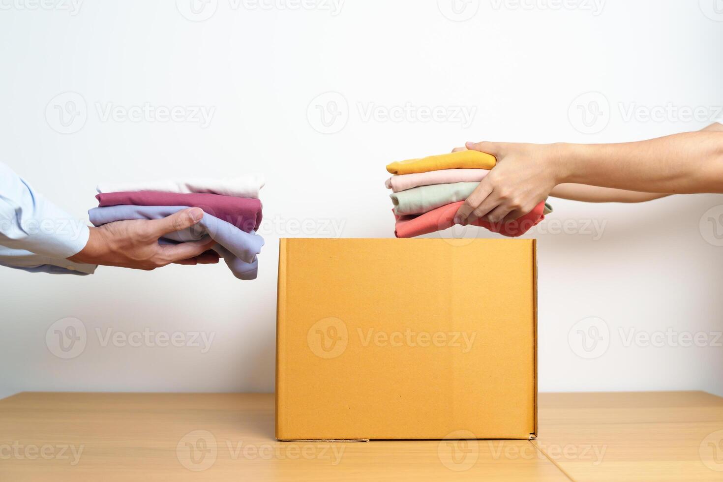 Donation, Charity, Volunteer, Giving, Delivery and Home Moving Concept. Hand holding Clothes into cardboard box at home for support and help poor, refugee and homeless people. Copy space for text photo
