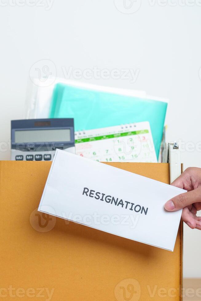 Resignation, Layoff, Unemployment, Dismiss, Job quit, Jobless and Farewell concept. Businessman holding letter of Resign contract with documents cardboard box at office photo
