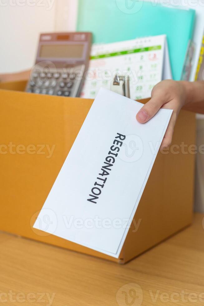 Resignation, Layoff, Unemployment, Dismiss, Job quit, Jobless and Farewell concept. Businesswoman holding letter of Resign contract with documents cardboard box at office photo
