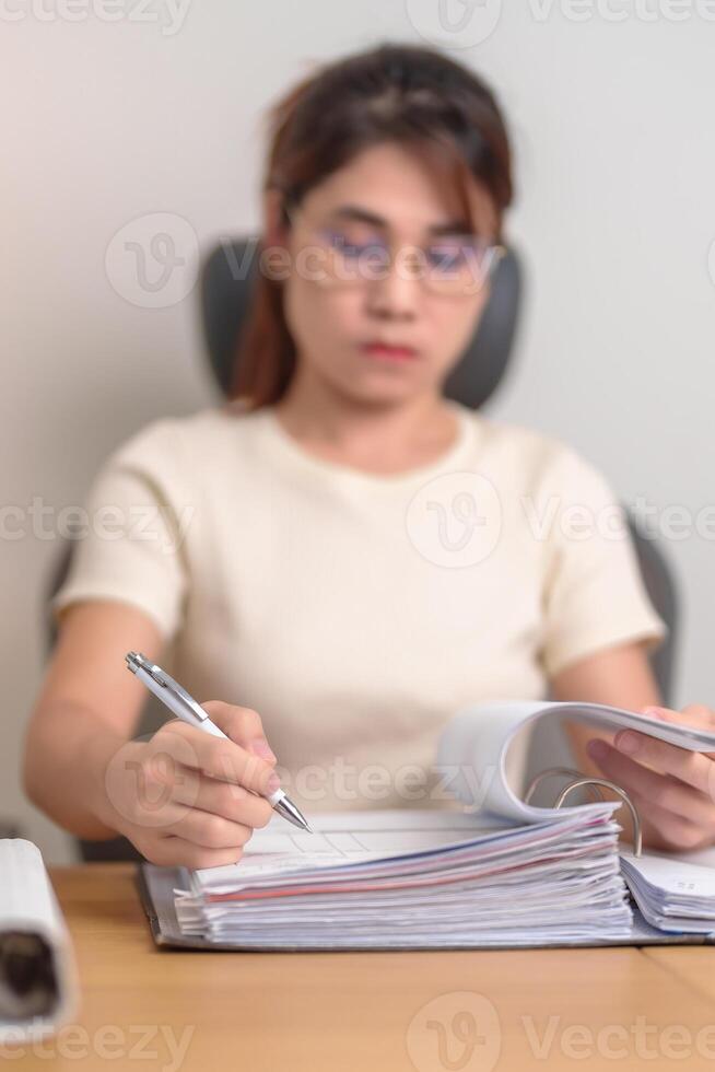 Asian woman reading financial report, female businesswoman sign contract or writing documents paper at home or office late night. Overworked, work hard and business concept photo