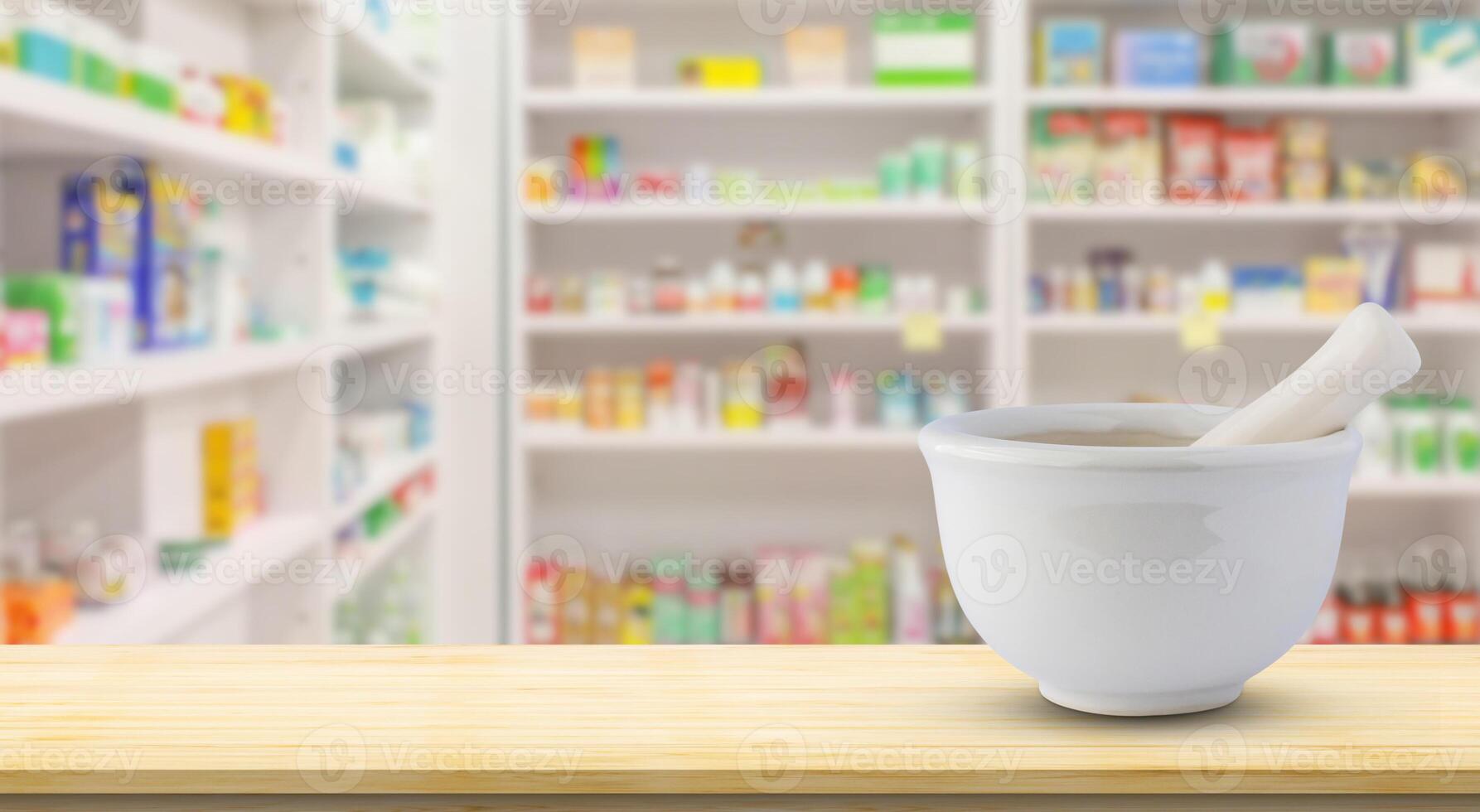Mortar and pestle on pharmacy counter top with blur medicine shelves in drugstore background photo