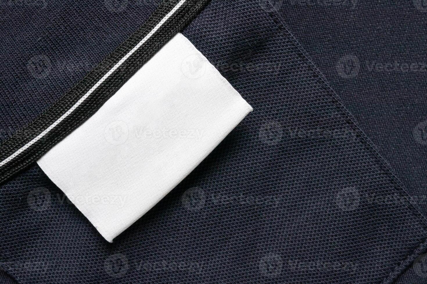 Blank white laundry care clothes label on black shirt fabric texture background photo