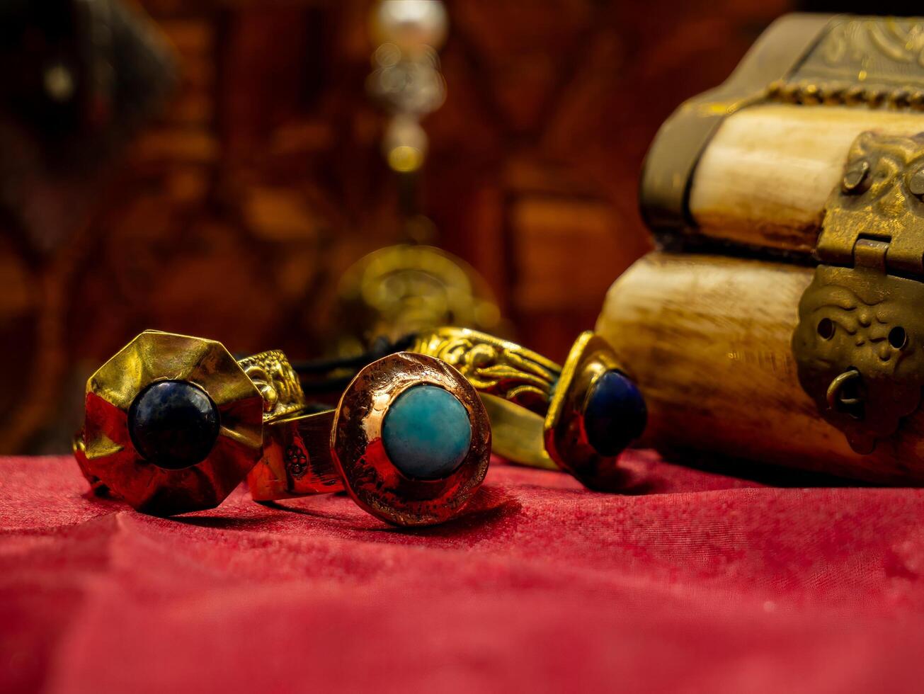 three reproductions of medieval rings decorated with precious gems on a red velvet background and a casket photo